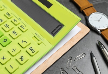 Photo of Calculator, watch and stationery on dark grey table, closeup. Tax accounting