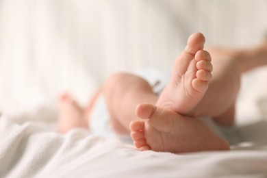 Photo of Cute newborn baby lying on bed, closeup of legs. Space for text