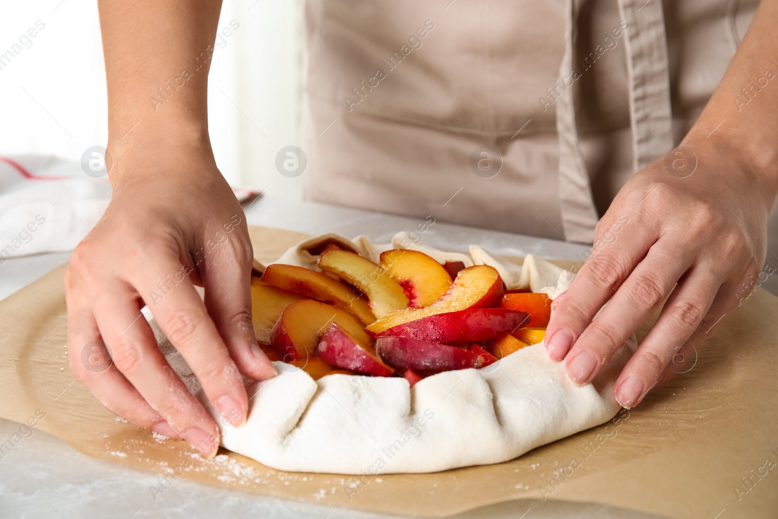 Photo of Woman making peach pie at kitchen table, closeup