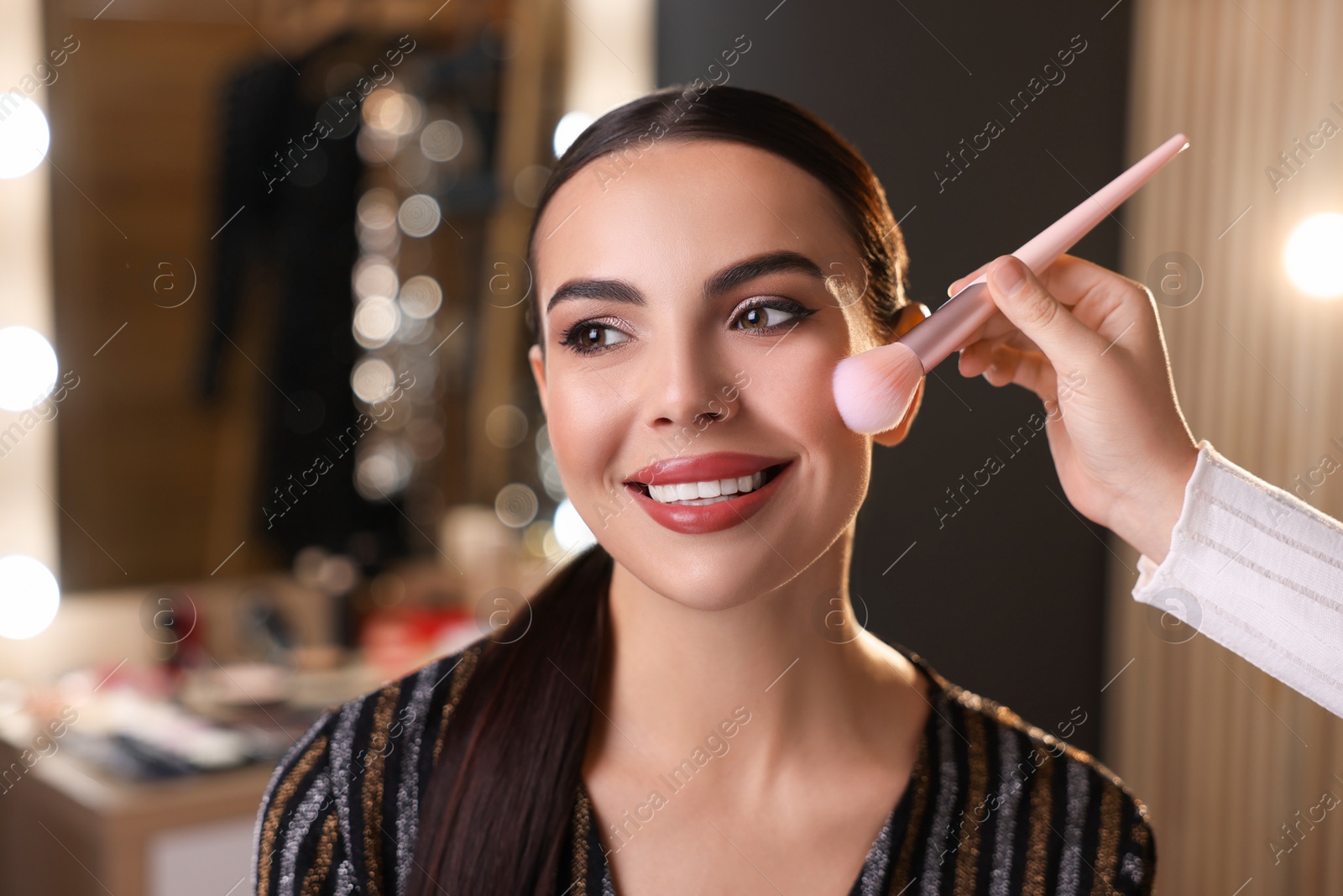 Photo of Makeup artist working with beautiful woman in dressing room