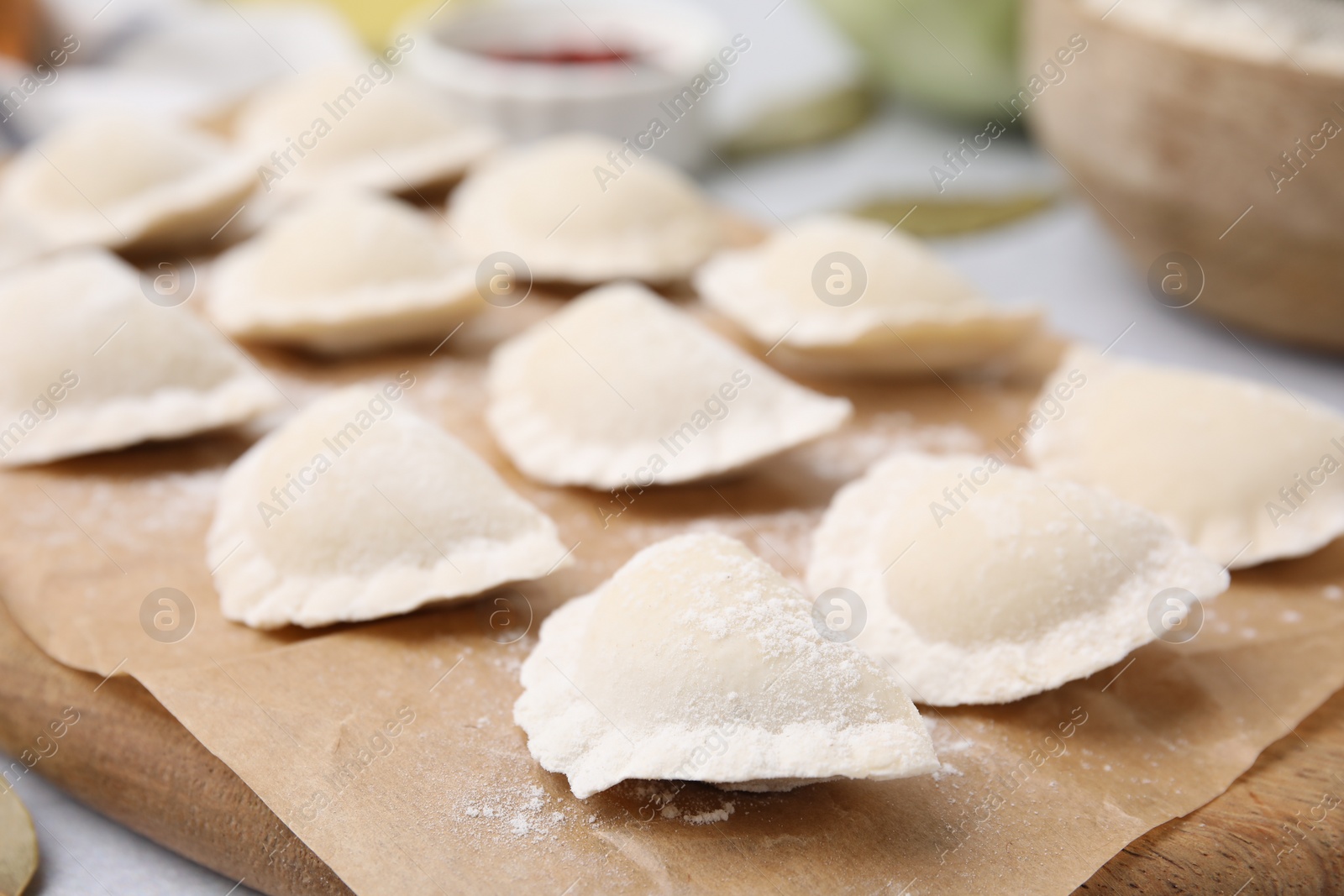 Photo of Raw dumplings (varenyky) with tasty filling on light grey table, closeup