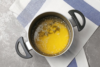 Photo of Pot with melting butter on grey table, top view