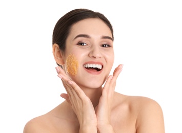 Young woman with natural scrub on her face against white background