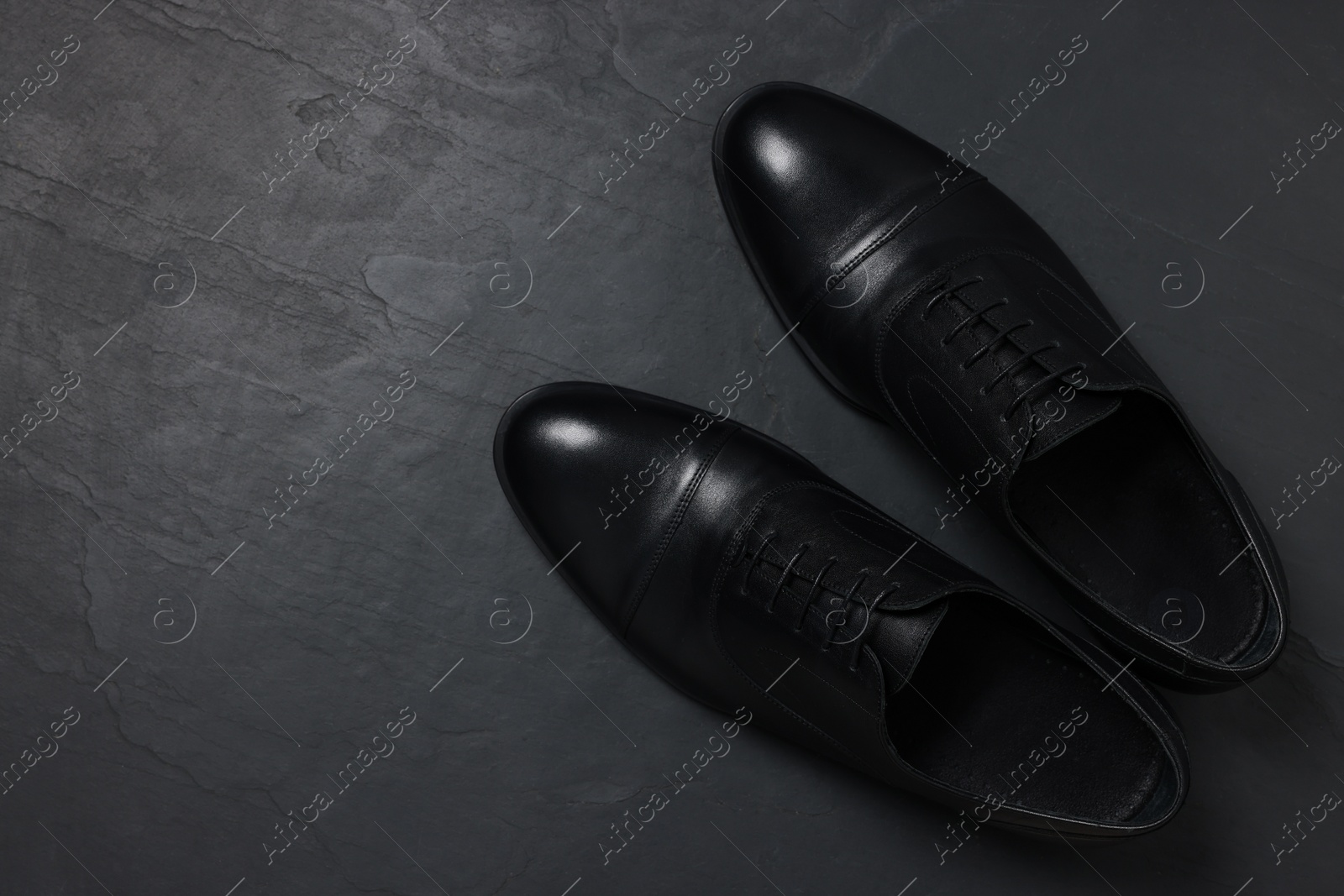 Photo of Pair of leather men shoes on black surface, top view. Space for text