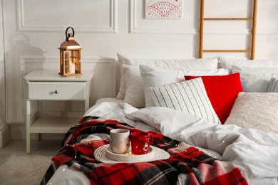 Photo of Christmas bedroom interior with red woolen blanket and decorative lantern