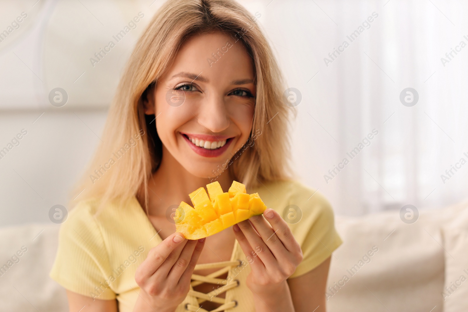 Photo of Young woman with fresh mango at home. Exotic fruit