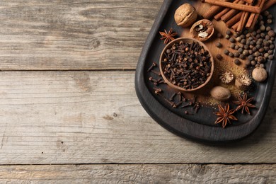 Different spices and nuts on wooden table, top view. Space for text