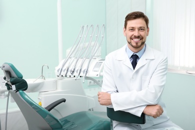 Photo of Professional male dentist in white coat at workplace. Space for text