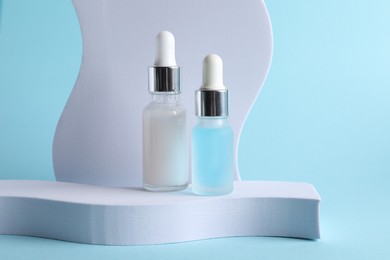 Stylish presentation of cosmetic serum on light blue background