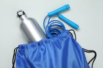 Photo of Blue drawstring bag, thermo bottle and skipping rope on grey background, top view