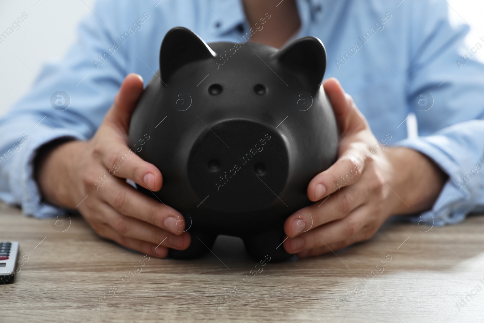Photo of Man with piggy bank at wooden table, closeup