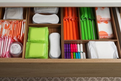 Photo of Storage of different feminine hygiene products in wooden drawer, above view