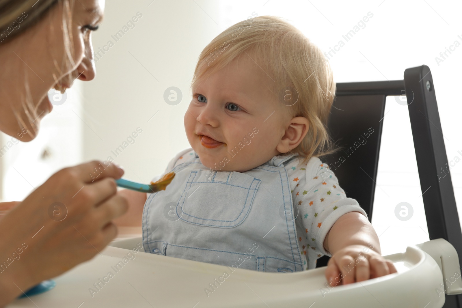 Photo of Mother feeding her cute little baby with healthy food at home