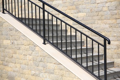 Photo of View of beautiful stairs with metal handrail near brick wall outdoors