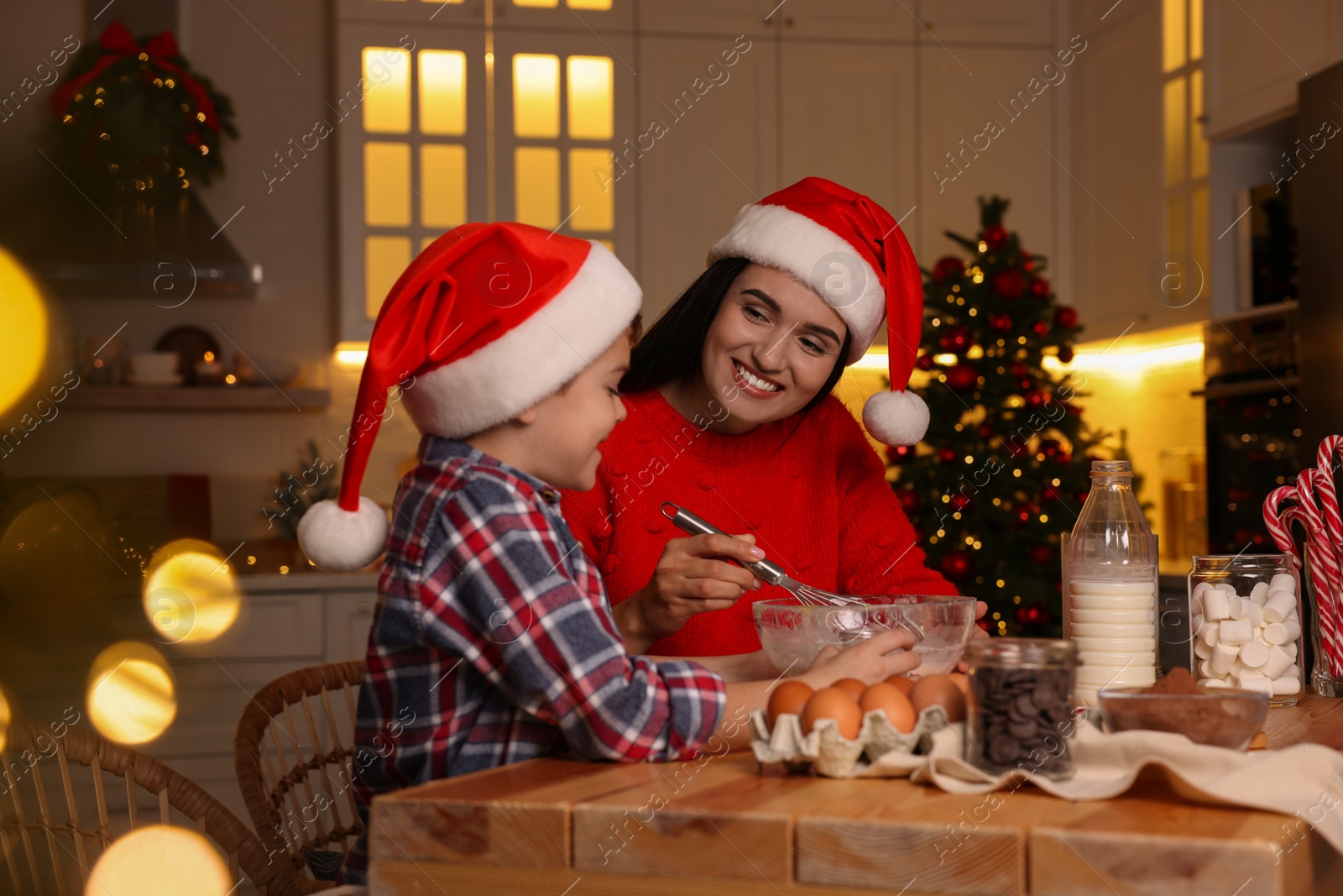 Photo of Happy mother and her son making dough for Christmas cookies at home