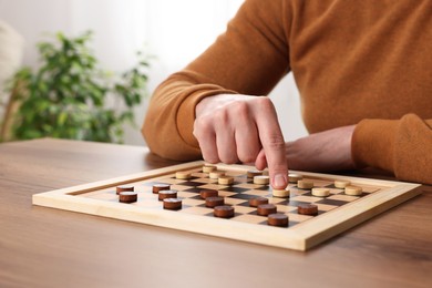 Photo of Man playing checkers at table in room, closeup