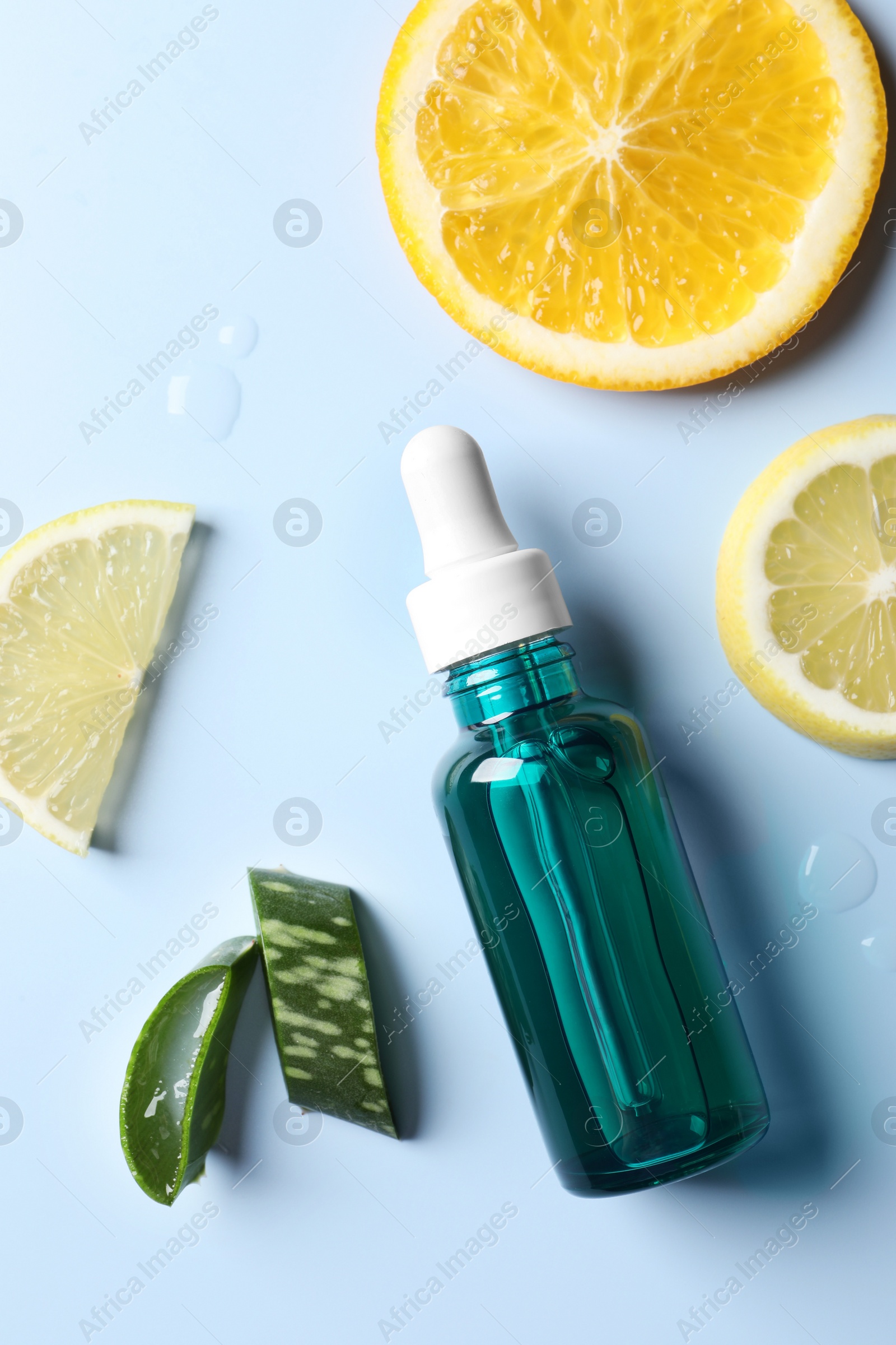 Photo of Bottle of cosmetic serum, sliced citrus fruits and aloe vera on light blue background, flat lay