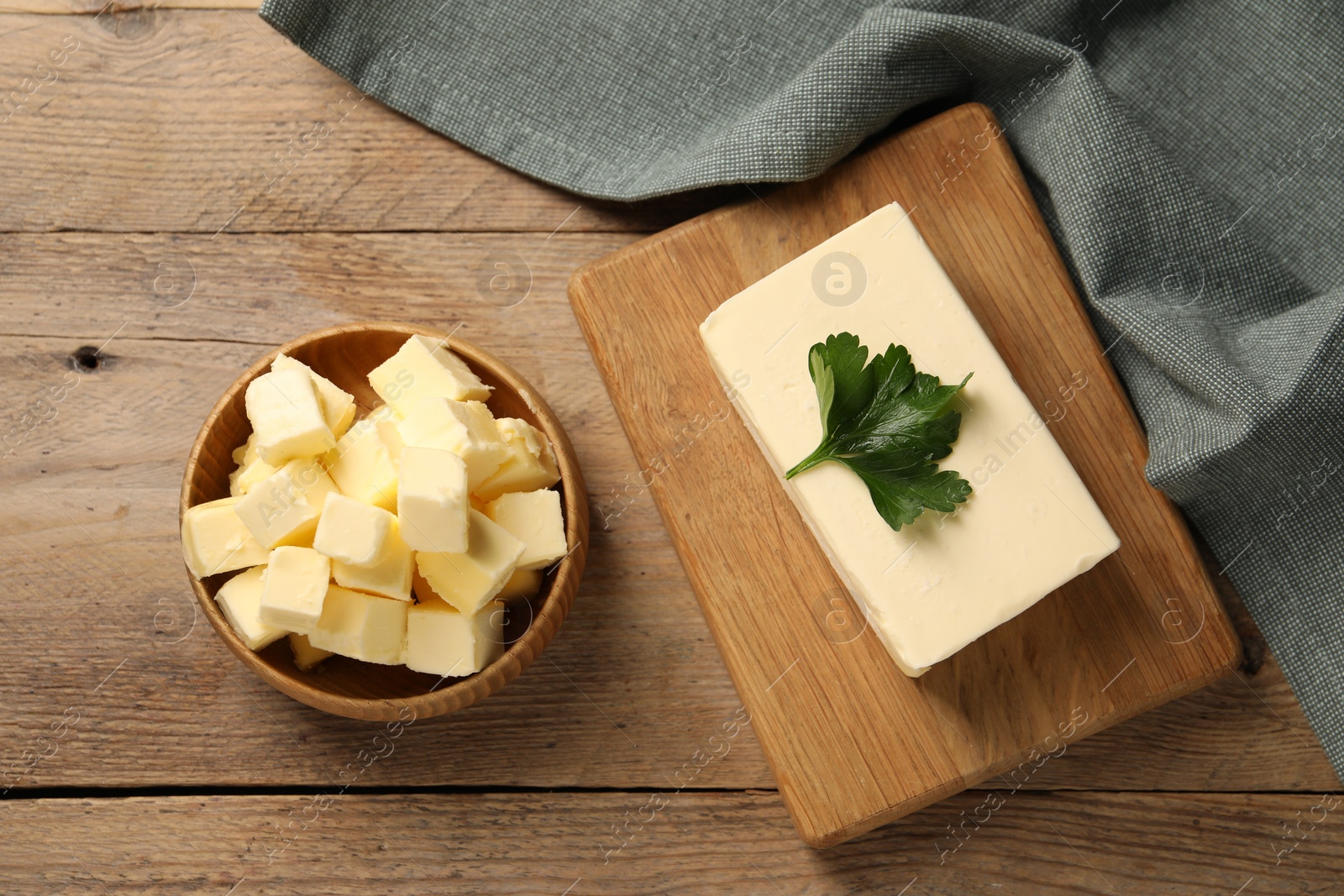 Photo of Tasty butter with parsley on wooden table, flat lay