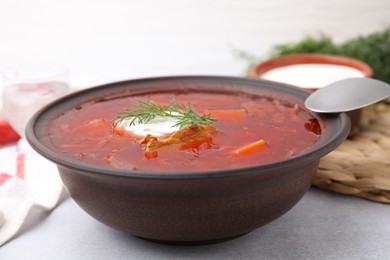 Tasty borscht with sour cream in bowl on grey table, closeup