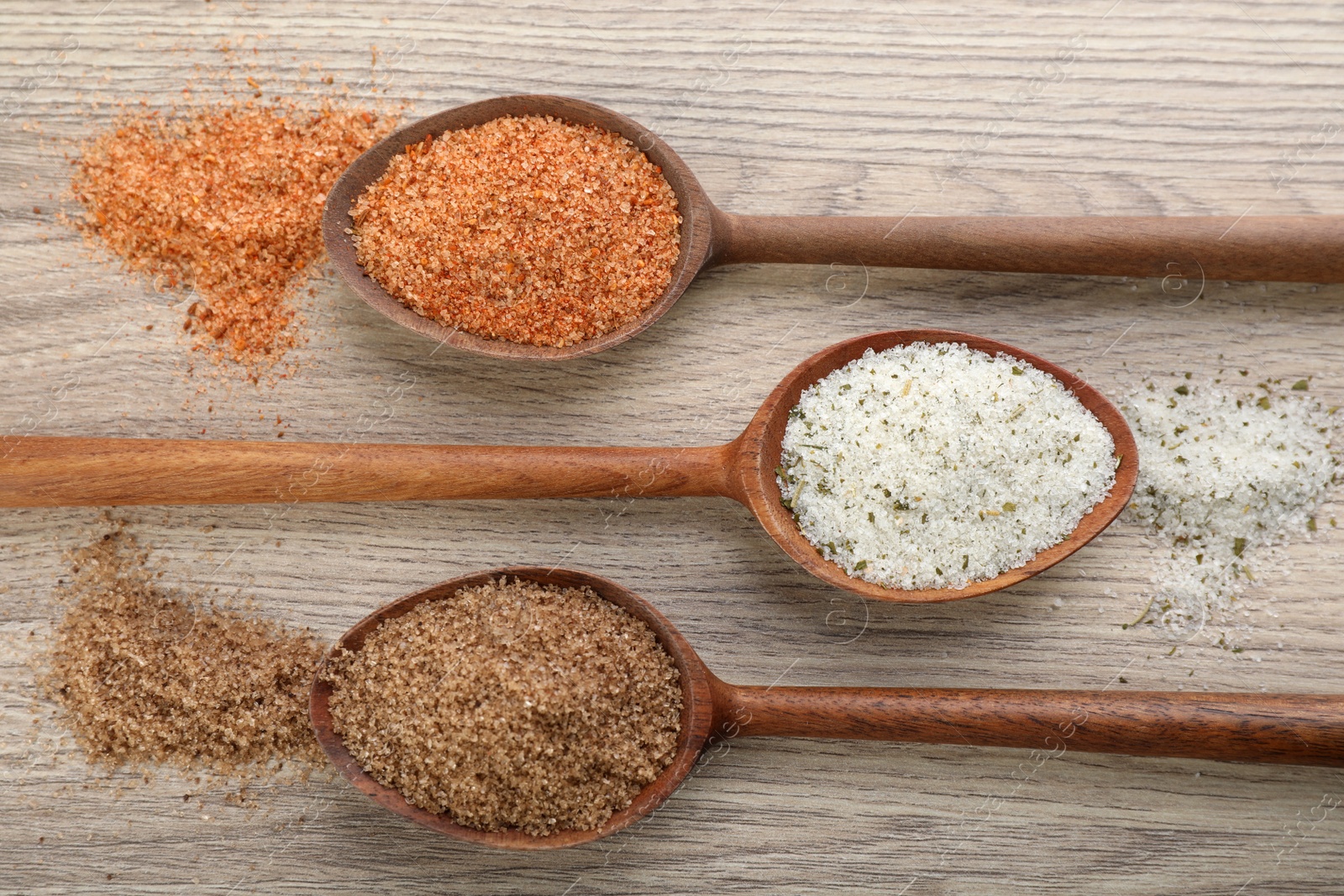 Photo of Different kinds of salt on wooden table, flat lay