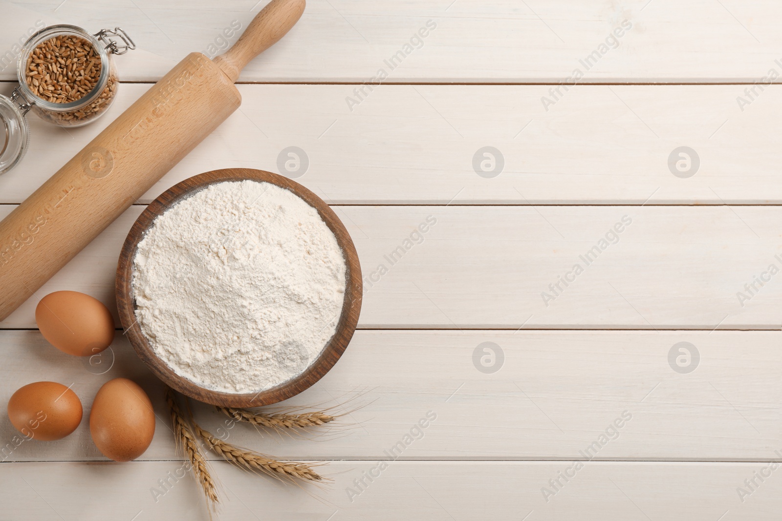 Photo of Flat lay composition with wheat flour and eggs on white wooden table. Space for text