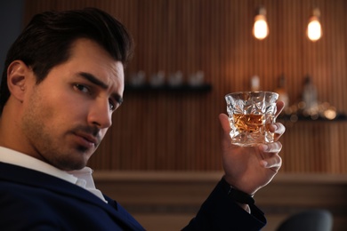 Young man with glass of whiskey in bar