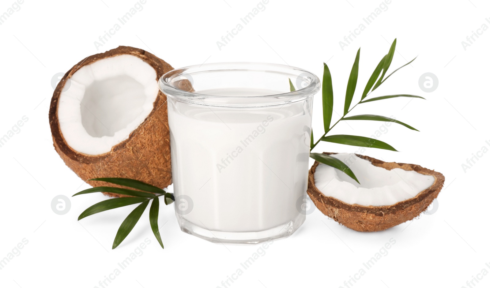 Photo of Glass of delicious vegan milk, coconut pieces and green leaves on white background
