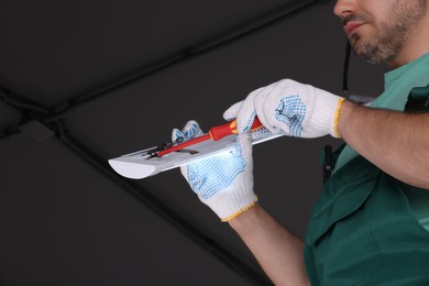 Photo of Ceiling light. Electrician installing led linear lamp indoors, closeup. Space for text