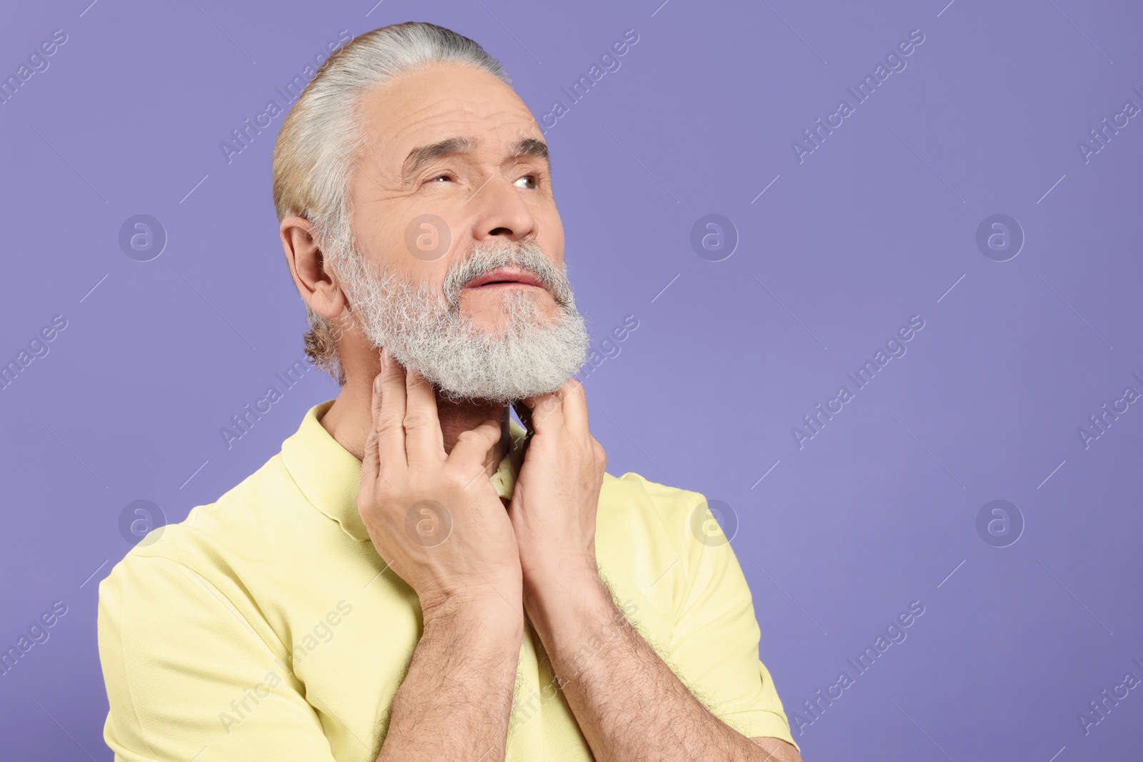 Photo of Senior man suffering from sore throat on light purple background, space for text. Cold symptoms