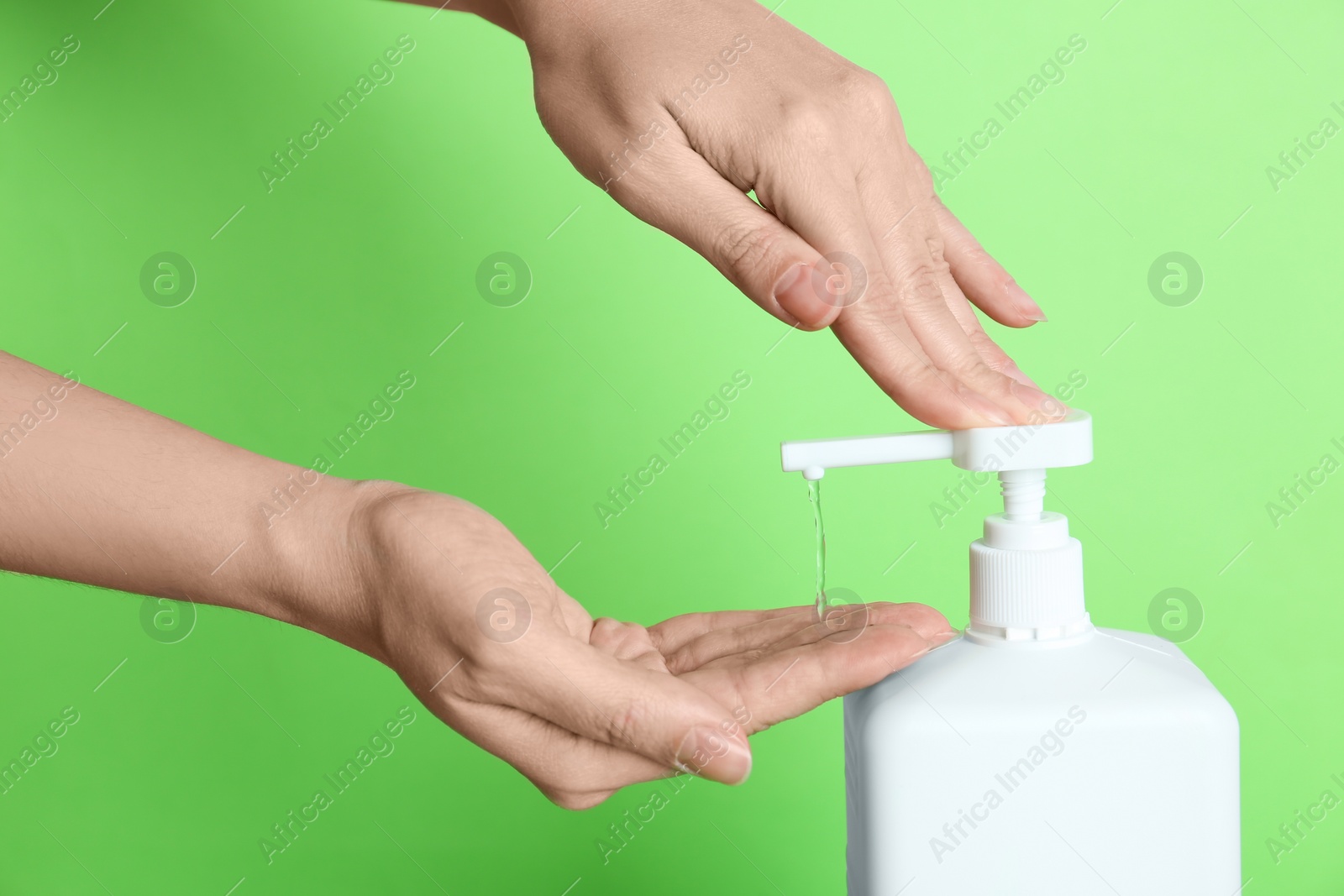 Photo of Woman applying antiseptic gel on hand against green background, closeup