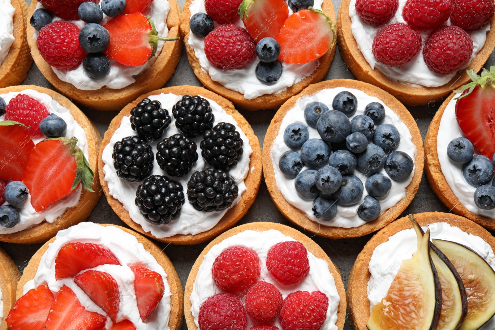 Photo of Many different berry tarts on table, top view. Delicious pastries