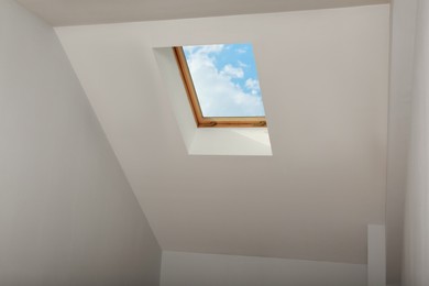 Photo of Skylight roof window and lamps on slanted ceiling in attic room, low angle view