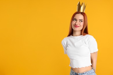 Photo of Beautiful young woman with princess crown on orange background, space for text
