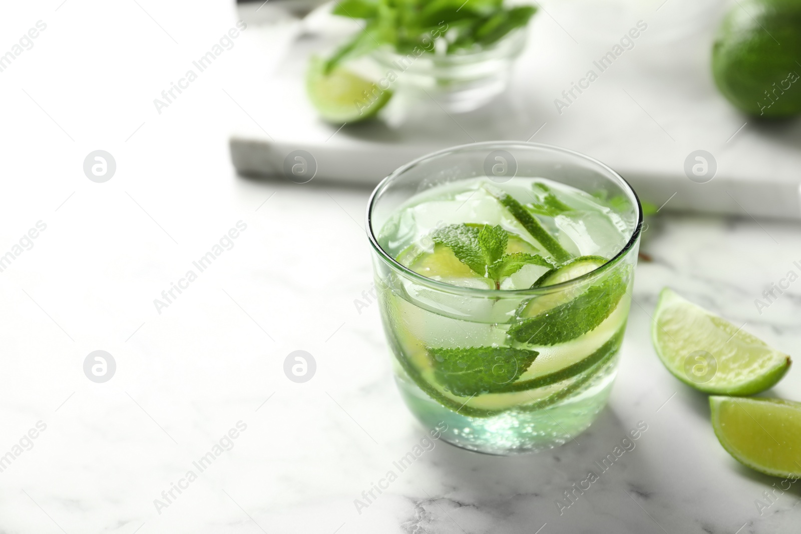 Photo of Refreshing beverage with mint and lime in glass on table