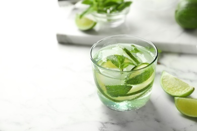 Refreshing beverage with mint and lime in glass on table