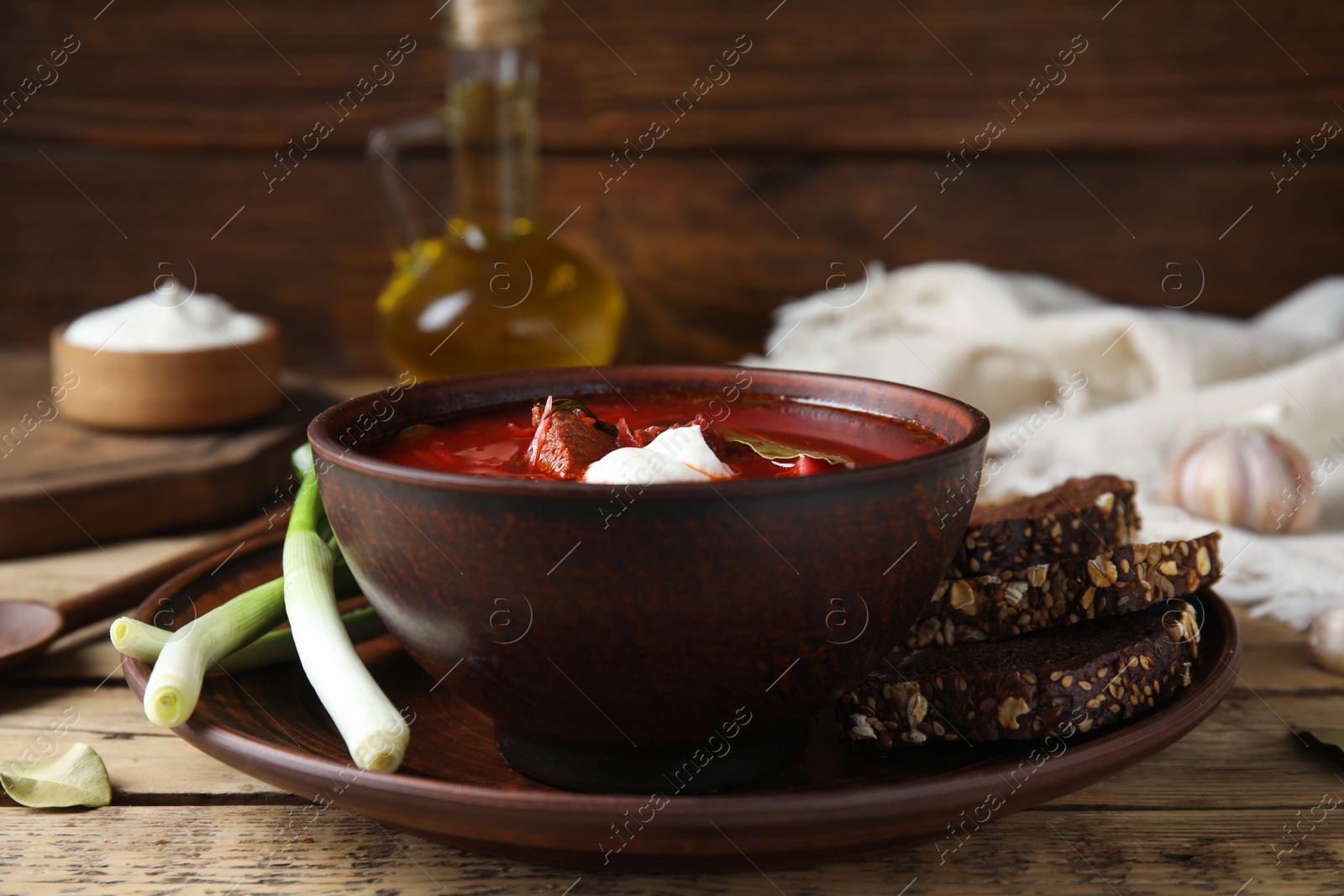 Photo of Clay bowl with Ukrainian borsch served on wooden table