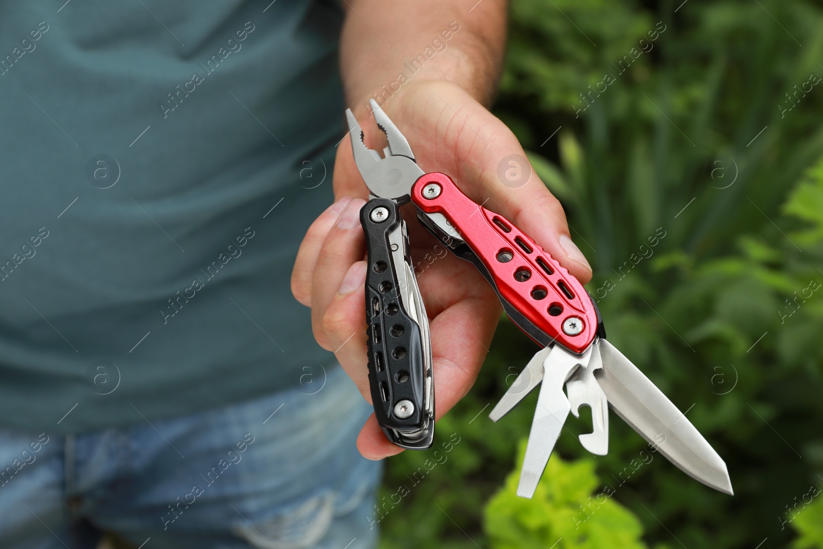 Photo of Man holding compact portable multitool outdoors, closeup