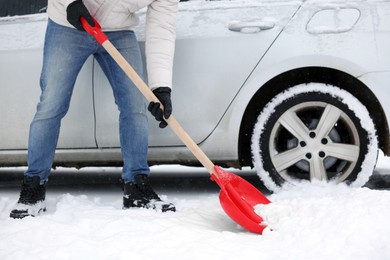 Man removing snow with shovel near car outdoors, closeup