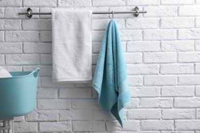 Hanger with clean towels on brick wall