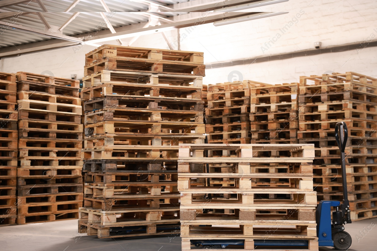 Image of Modern manual forklift and wooden pallets in warehouse