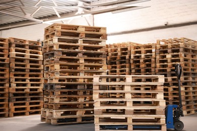 Modern manual forklift and wooden pallets in warehouse