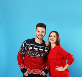 Couple wearing Christmas sweaters on blue background