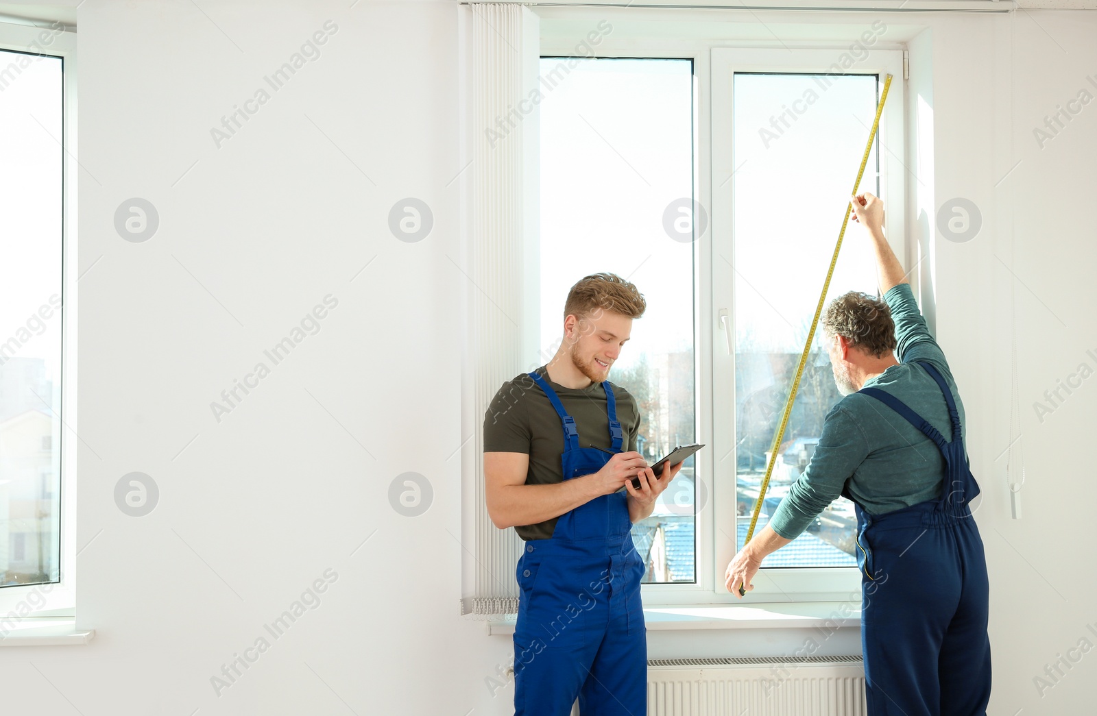 Photo of Service men measuring window for installation indoors. Space for text