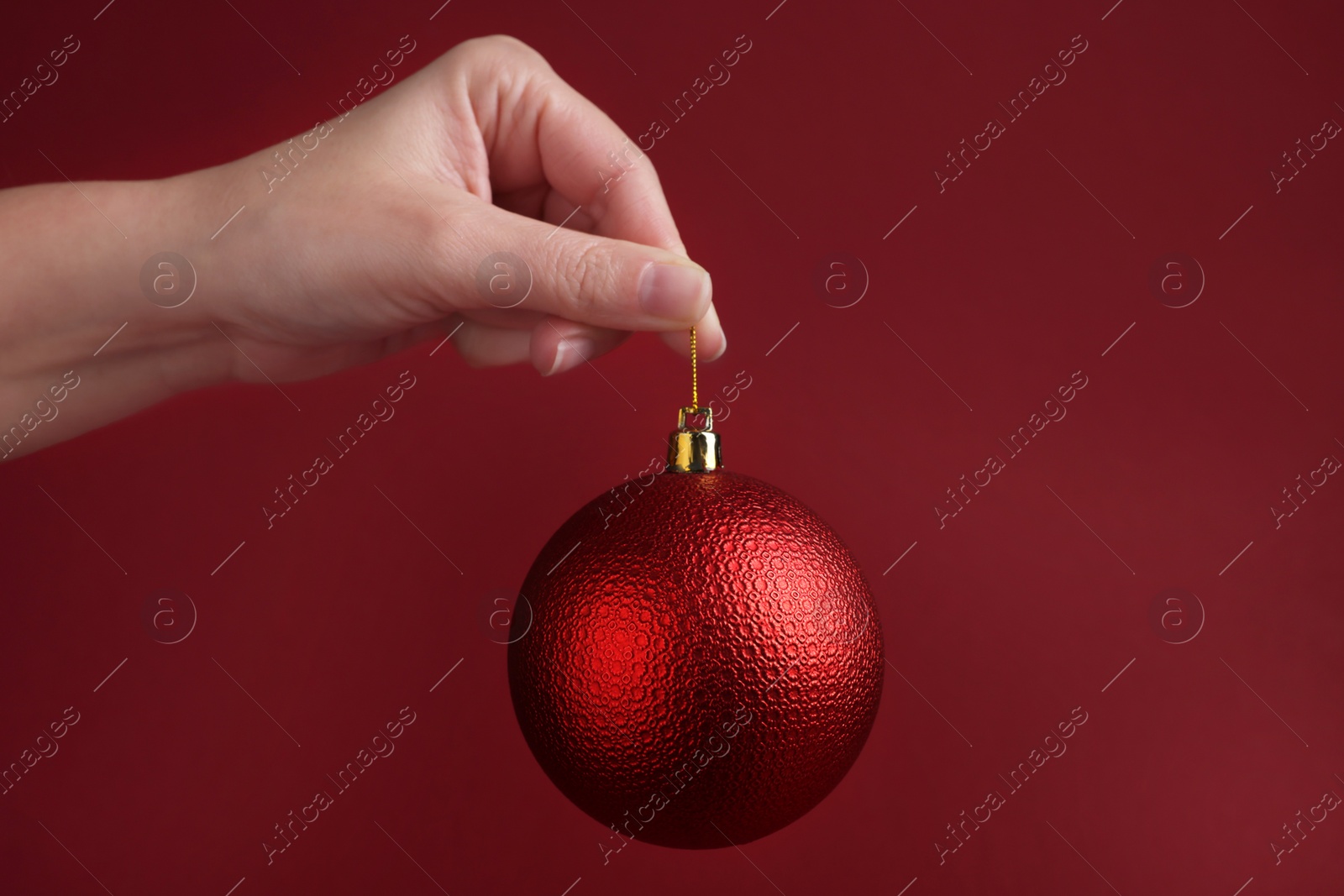 Photo of Woman holding beautiful Christmas ball on red background, closeup