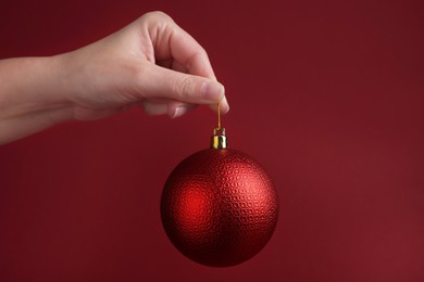 Photo of Woman holding beautiful Christmas ball on red background, closeup