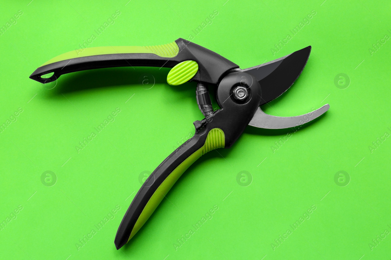 Photo of Secateur on green background, top view. Gardening tool