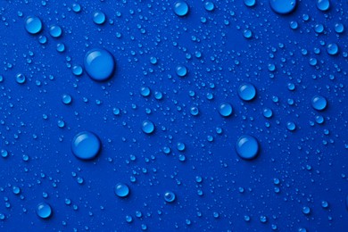 Water drops on blue background, top view