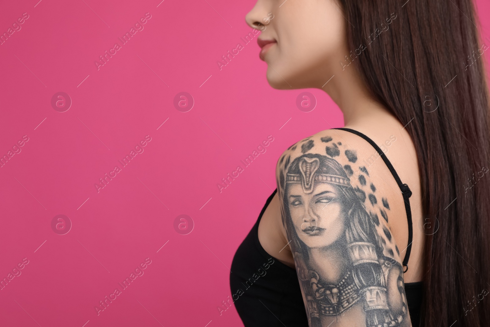 Photo of Woman with tattoos on arm against pink background, closeup. Space for text