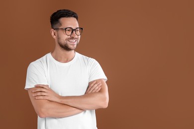 Portrait of happy man in stylish glasses on brown background. Space for text