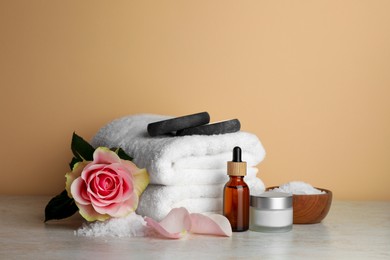 Photo of Composition with different spa products and rose on beige table. Space for text